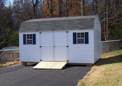 12 x 16 V-High Barn with white siding and trim, estate gray shingles and bedford blue shutters with a treated wooden ramp.
