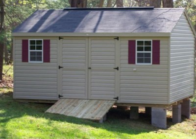 12 x 16 V-A-roof with tan siding and trim, estate gray shingles and maroon shutters and treated wooden ramp