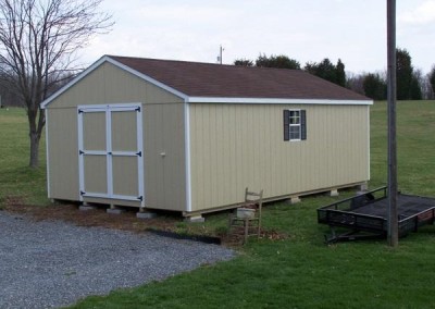 Painted 14x24 shed with a shingle, a-roof style roof. Shed has white trim and a set of solid double doors. Shed has a pair of windows with shutters
