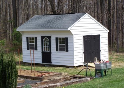 12 x 16 V-Carriage with white siding and trim, estate gray shingles, black shutters, ridge vent, fiber doors and composite door with circle top window