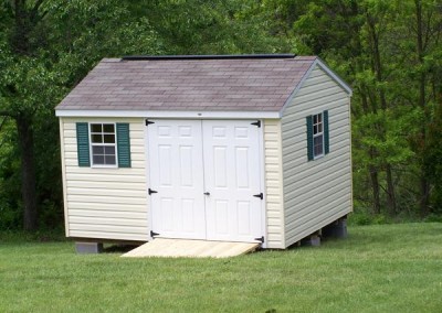 10 x 12 V-A-roof with cream siding, white trim, driftwood shingles, green shutters, fiber doors and a ridgevent