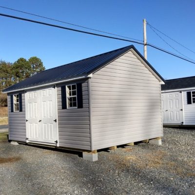 12x16 size vinyl classic style shed with flint siding, white trim, black metal roof, black shutters, and 6 foot fiber doors with two windows.