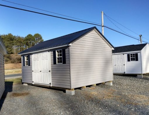 12x16 size vinyl classic style shed with flint siding, white trim, black metal roof, black shutters, and 6 foot fiber doors with two windows.