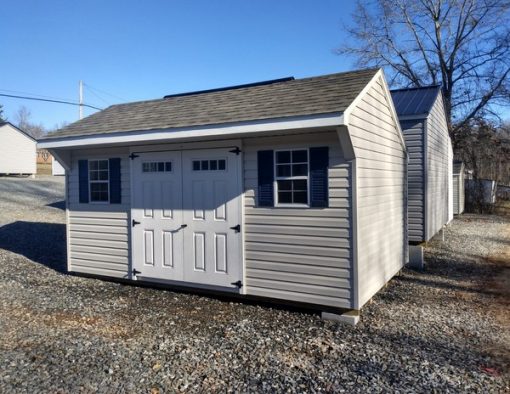 10x16 size vinyl carriage roof style shed with mist siding, white trim, driftwood architectural shingle roof, navy blue shutters. Has 8' ridge