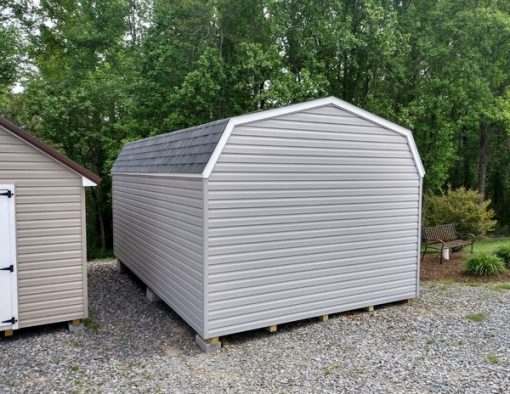 12x20 size vinyl high barn roof style shed with flint siding, white trim, estate gray architectural shingle roof, black shutters. Has ridgevent, 6 foot fiber doors and two windows.