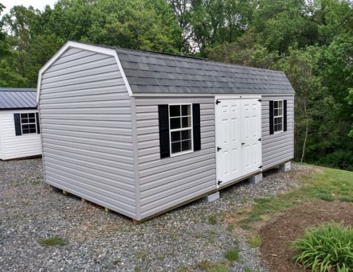 12x20 size vinyl high barn roof style shed with flint siding, white trim, estate gray architectural shingle roof, black shutters. Has ridgevent, 6 foot fiber doors and two windows.
