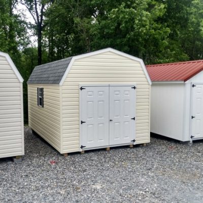 10x16 size vinyl high barn roof style shed with cream siding, white trim, estate gray architectural shingle roof, gray shutters. Has 8' ridge vent, 6 foot fiber doors and two windows.