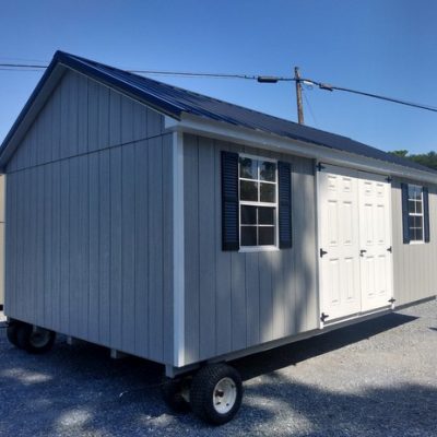 12 x 20 size painted classic style shed with gap gray siding, white trim, black metal roof, black shutters, fiber solid 6 foot shed doors and two windows.