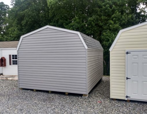 12x16 size vinyl high barn roof style shed with flint siding, white trim, estate gray architectural shingle roof, black shutters. Has ridgevent, 6 foot fiber doors and two windows.