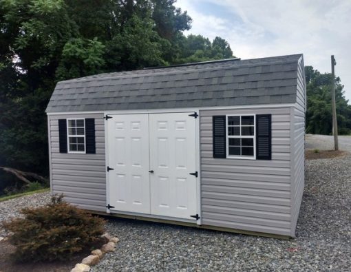 12x16 size vinyl high barn roof style shed with flint siding, white trim, estate gray architectural shingle roof, black shutters. Has ridgevent, 6 foot fiber doors and two windows.