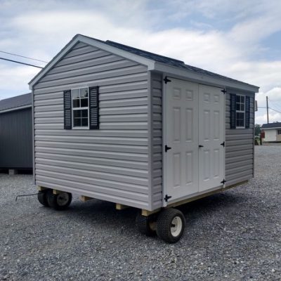 10x12 size vinyl a-roof style shed with flint siding, white trim, estate gray architectural shingle roof, black shutters. Has ridgevent, 6 foot fiber doors and two windows.