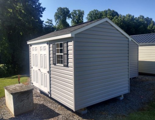 8x12 size vinyl a-roof style shed with flint siding, white trim, black architectural shingle roof, black shutters. Has ridgevent, 6 foot fiber doors and one window.
