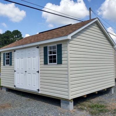12x16 size vinyl classic roof style shed with almond siding, white trim, desert tan architectural shingle roof, green shutters. Has ridgevent, 6 foot fiber doors and two windows.