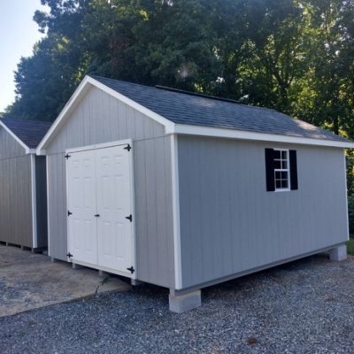 12 x 16 size painted classic style shed with gap gray siding, white trim, black architectural shingle roof, black shutters, 8' ridgevent, fiber solid 6 foot shed doors, two windows.
