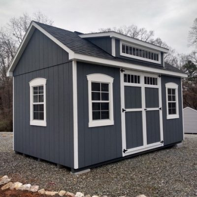 10 x 16 size painted garden style shed with gray siding, white trim, black architectural shingle roof, white royal trim instead of shutters, shed dormer, transom window, 1' ft taller walls, 8' ridge vent, ggs transom 6 foot doors, 1' ft taller, (4) 24"x36" windows with royal trim.