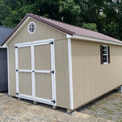 10 x 16 size painted classic style shed with tan siding, white trim, brown metal roof, brown shutters, ggs 6 foot doors, one octagon window, two windows.