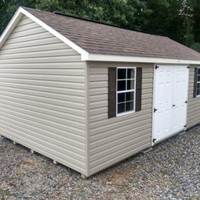 12x20 size vinyl classic roof style shed with clay siding, pearl trim, brownwood architectural shingle roof, brown shutters. Has ridgevents, 6 foot fiber doors and two windows.