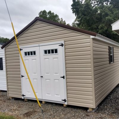 12x16 size vinyl a-roof roof style shed with tan siding, white trim, brown metal roof, brown shutters. has 6 foot fiber transom doors and two windows.