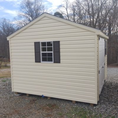 10x12 size vinyl a-roof roof style shed with cream siding, cream trim, desert tan architectural shingle roof, brown shutters. Has 8' ridgevent, 6 foot double doors and two windows.