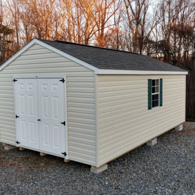 12x20 size vinyl a-roof style shed with almond siding, white trim, driftwood architectural shingle roof, green shutters. Has 2 ridgevents, 6 foot fiber doors and two windows.