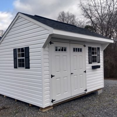10x12 size vinyl carriage roof style shed with white siding, white trim, black architectural shingle roof, black shutters. Has 8' ridgevent, 1 flowerbox, 6 foot transom double doors and two windows.