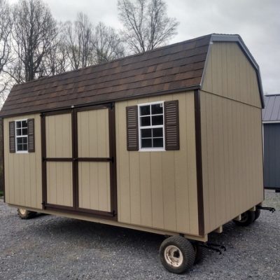 10 x 16 size painted high barn style shed with tan siding, brown trim, brownwood architectural shingle roof, brown shutters, 8' ridge vent, ggs 6 foot double doors, two windows.