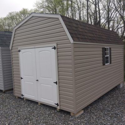 10x16 size vinyl high barn roof style shed with clay siding, mist trim, brownwood architectural shingle roof, brown shutters. has 8' ridge vent, 6 foot fiber 2 plank doors and two windows.