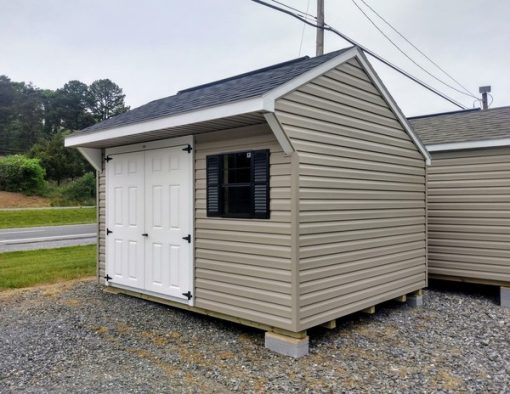 10x12 size vinyl carriage roof style shed with clay siding, white trim, black architectural shingle roof, black shutters. Has ridgevent, 6 foot fiber doors and two black windows.