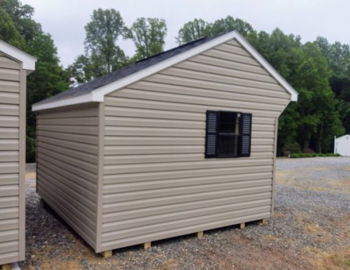 10x12 size vinyl carriage roof style shed with clay siding, white trim, black architectural shingle roof, black shutters. Has ridgevent, 6 foot fiber doors and two black windows.