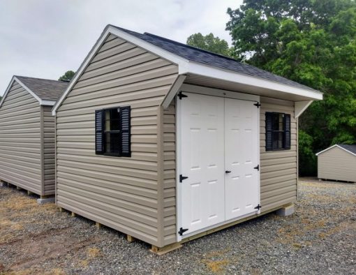 10x12 size vinyl carriage roof style shed with clay siding, white trim, black architectural shingle roof, black shutters. Has ridgevent, 6 foot fiber doors and two black windows.