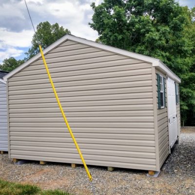 12x16 size vinyl a-roof style shed with clay siding, white trim, driftwood architectural shingle roof, green shutters. has (1) 8' ridge vent, 6 foot fiber double shed doors and two windows.