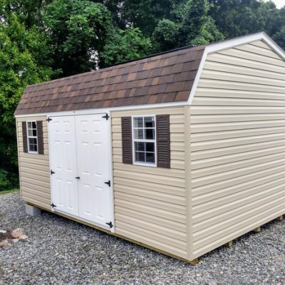 12x16 size vinyl high barn roof style shed with tan siding, white trim, brownwood architectural shingle roof, brown shutters. has 8' ridge vent, 6 foot fiber double doors and two windows.