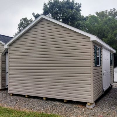 12x16 size vinyl classic style shed with clay siding, white trim, driftwood architectural shingle roof, green shutters. has (1) 8' ridge vent, 6 foot fiber double shed doors and two windows.