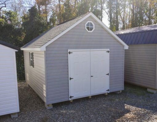 12x16 size vinyl garden roof style shed with flint siding, white trim, black architectural shingle roof, black shutters. has (1) 8' ridge vent, (1) octagon window, 6 foot fiber doors and two windows.