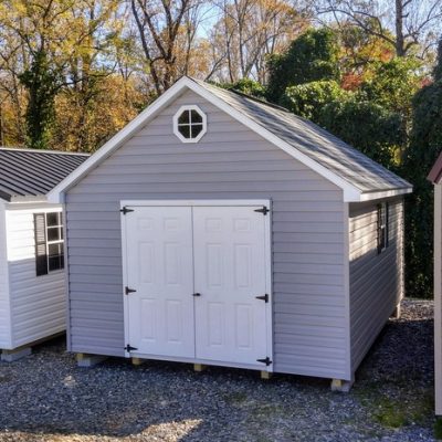 12x16 size vinyl garden roof style shed with flint siding, white trim, black architectural shingle roof, black shutters. has (1) 8' ridge vent, (1) octagon window, 6 foot fiber doors and two windows.