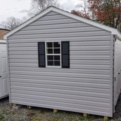 10x12 size vinyl a-roof style shed with flint siding, white trim, black architectural shingle roof, black shutters. has (1) 8' ridge vent, 6 foot fiber doors and two windows.