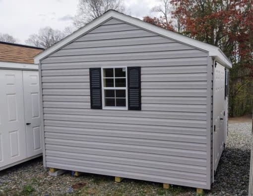 10x12 size vinyl a-roof style shed with flint siding, white trim, black architectural shingle roof, black shutters. has (1) 8' ridge vent, 6 foot fiber doors and two windows.