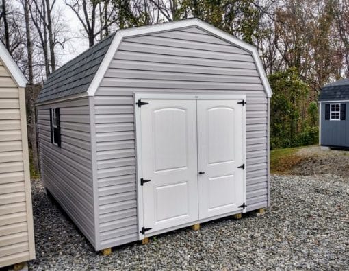 10x16 size vinyl high barn roof style shed with flint siding, white trim, black architectural shingle roof, black shutters. has (1) 8' ridge vent, 6 foot fiber 2 plank double doors and two windows.