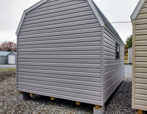 10x16 size vinyl high barn roof style shed with flint siding, white trim, black architectural shingle roof, black shutters. has (1) 8' ridge vent, 6 foot fiber 2 plank double doors and two windows.