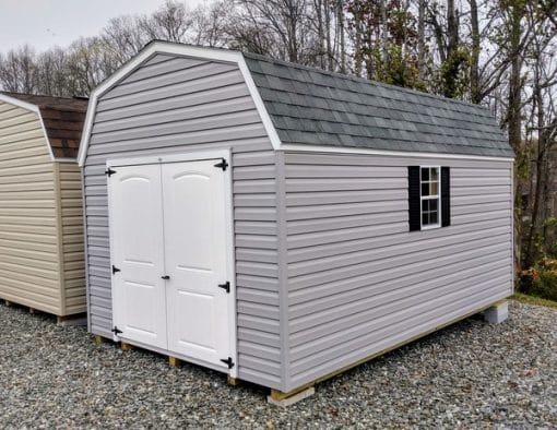 10x16 size vinyl high barn roof style shed with flint siding, white trim, black architectural shingle roof, black shutters. has (1) 8' ridge vent, 6 foot fiber 2 plank double doors and two windows.