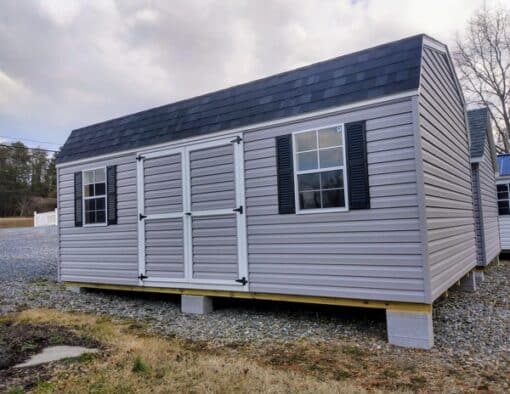 12x20 size vinyl high barn roof style shed with flint siding, white trim, black architectural shingle roof, black shutters. has (2) 8' ridge vents, ggs 6 foot double doors and two windows.