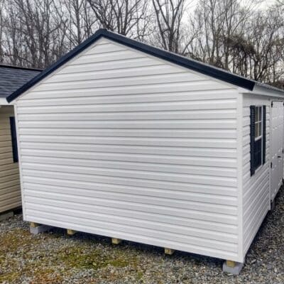 12x20 size vinyl a-roof style shed with white siding, white trim, black metal roof, black shutters. Has 6 foot fiber double doors and two windows.