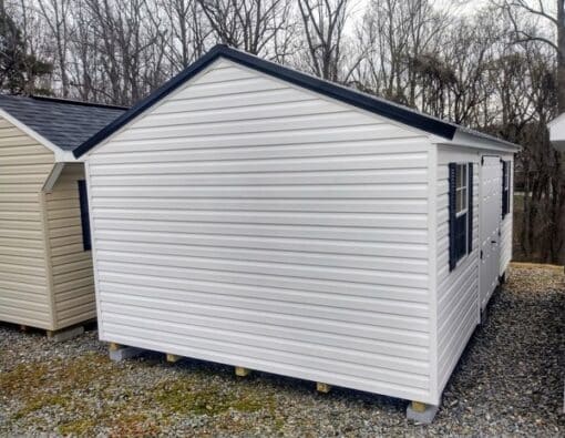 12x20 size vinyl a-roof style shed with white siding, white trim, black metal roof, black shutters. Has 6 foot fiber double doors and two windows.