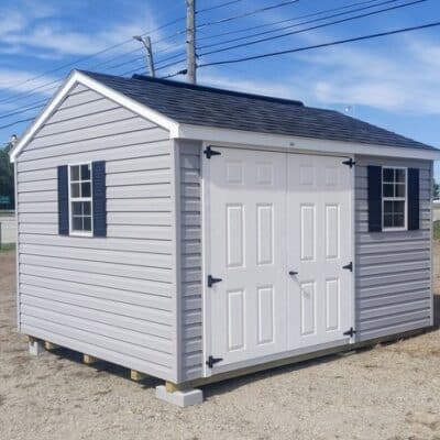 10x12 size vinyl a-roof style shed with flint siding, white trim, black architectural shingle roof, black shutters. has (1) 8' ridge vent, 6 foot fiber doors and two windows.
