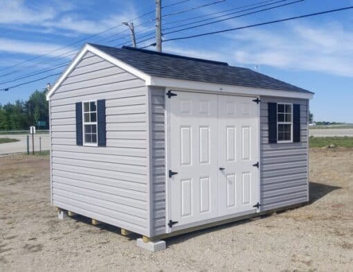 10x12 size vinyl a-roof style shed with flint siding, white trim, black architectural shingle roof, black shutters. has (1) 8' ridge vent, 6 foot fiber doors and two windows.