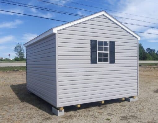 10x12 size vinyl a-roof style shed with flint siding, white trim, black architectural shingle roof, black shutters. has (1) 8' ridge vent, 6 foot fiber doors and two windows.