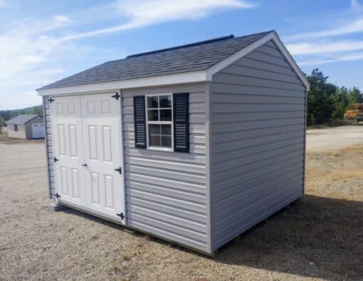 10x12 size vinyl a-roof style shed with flint siding, white trim, black architectural shingle roof, black shutters. has (1) 8' ridge vent, 6 foot fiber doors and two windows.