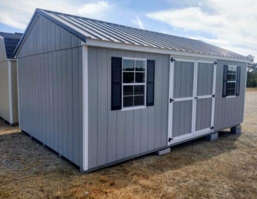 12 x 20 size painted a-roof style shed with gap gray siding, white trim, black metal roof, black shutters, ggs 6 foot doors, two windows.