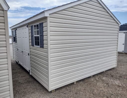 12x16 size vinyl a-roof style shed with almond siding, white trim, estate gray architectural shingle roof, gray shutters. has (1) 8' ridge vent, 6 foot fiber doors and two windows.