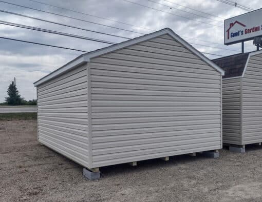 12x16 size vinyl a-roof style shed with almond siding, white trim, estate gray architectural shingle roof, gray shutters. has (1) 8' ridge vent, 6 foot fiber doors and two windows.